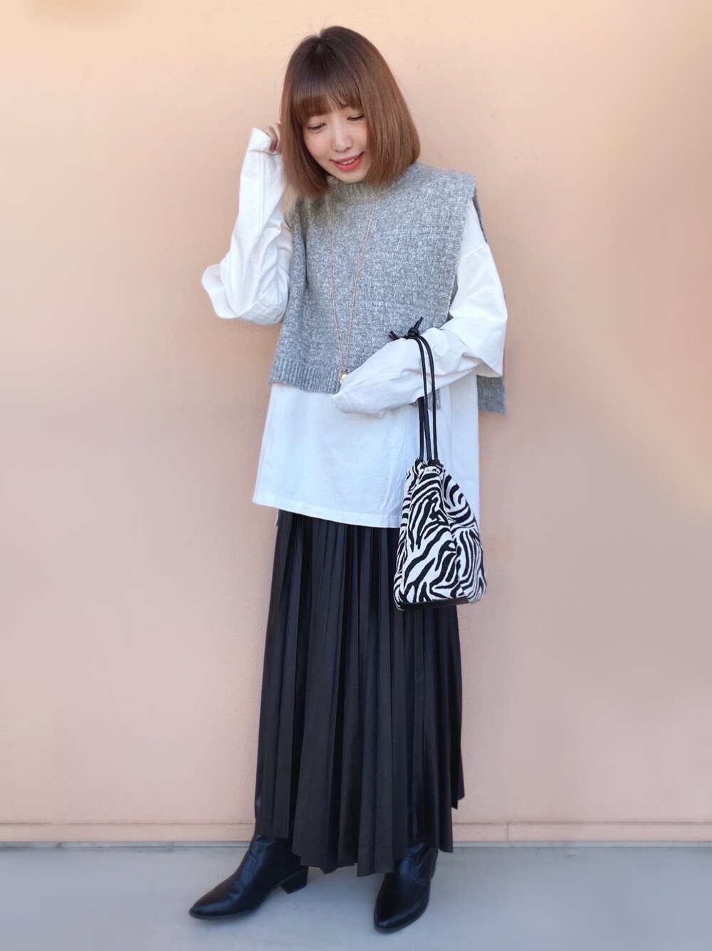 ブラック系のスカート、ブラック系のショルダーバッグ、ブラック系のブーツを着用したレディースの冬コーディネートの1枚目の写真