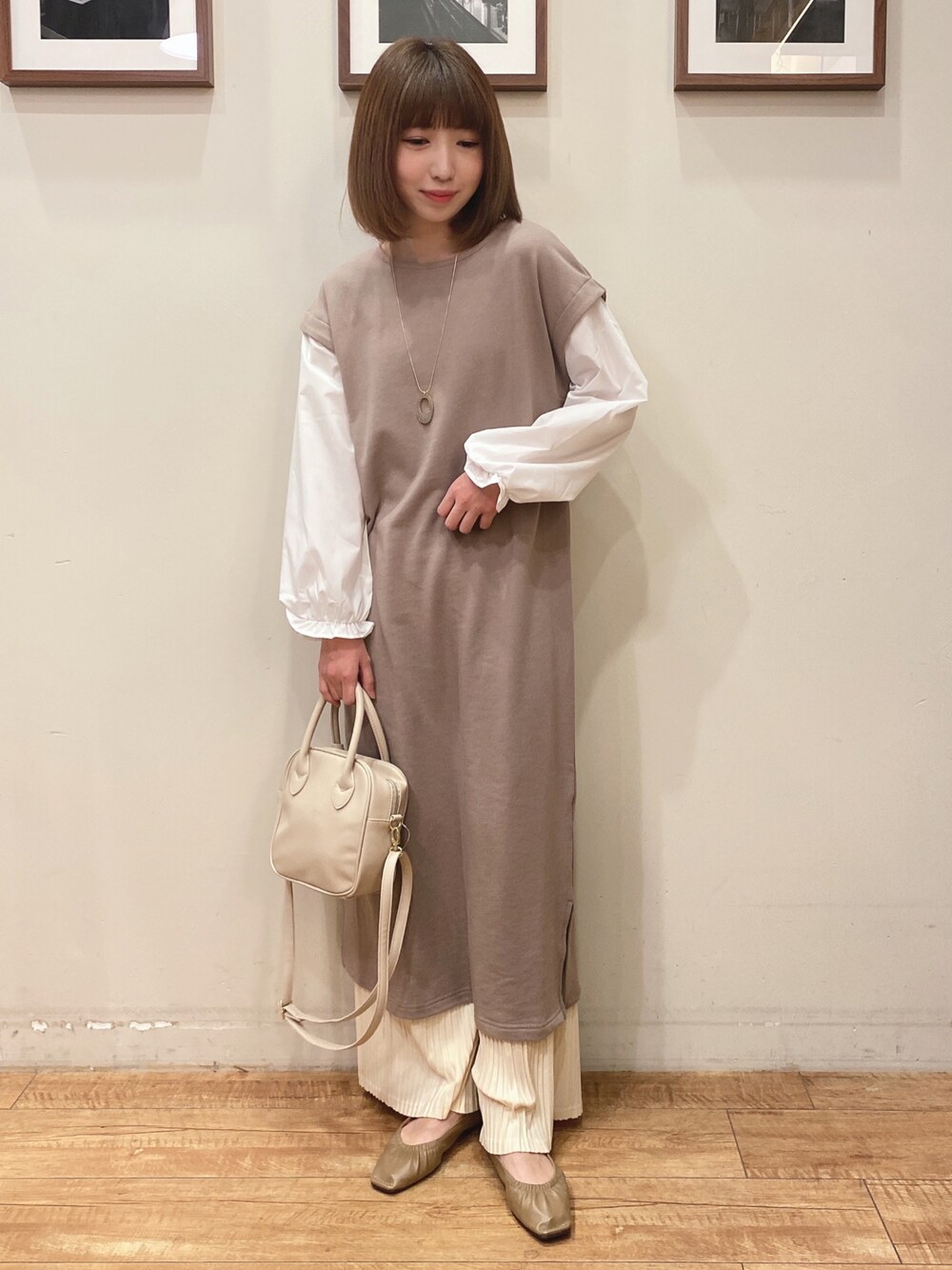 ベージュ系のワンピース、ベージュ系のパンプス、ホワイト系のショルダーバッグを着用したレディースの冬コーディネートの1枚目の写真