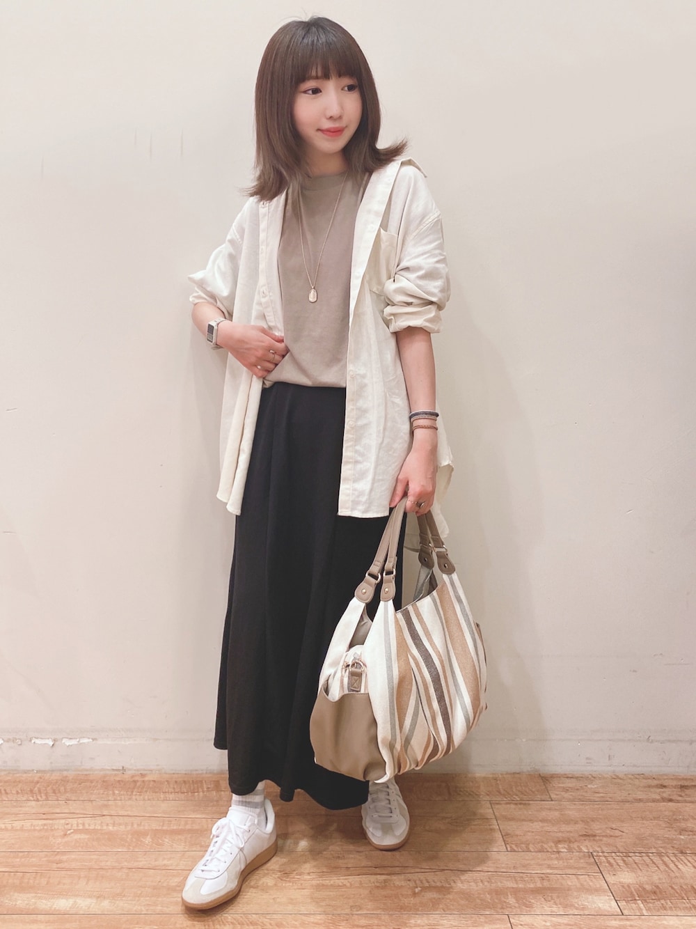 グリーン系のTシャツ/カットソー、ホワイト系のシャツ/ブラウス、ブラック系のスカートを着用したレディースの春コーディネートの1枚目の写真