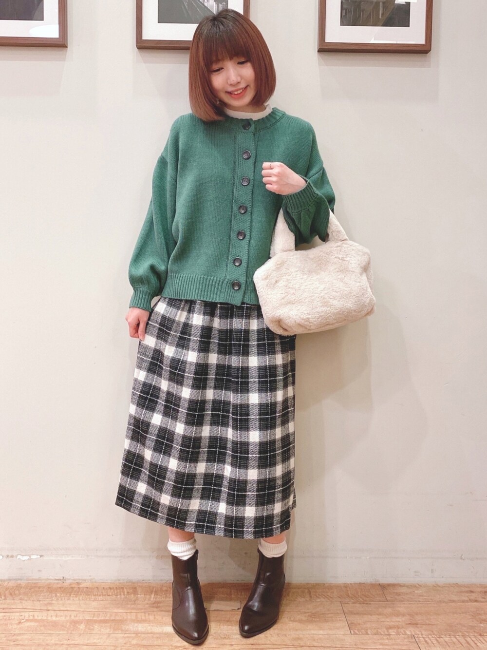 グリーン系のカーディガン/ボレロ、ホワイト系のトートバッグ、グレー系のスカートを着用したレディースの冬コーディネートの1枚目の写真