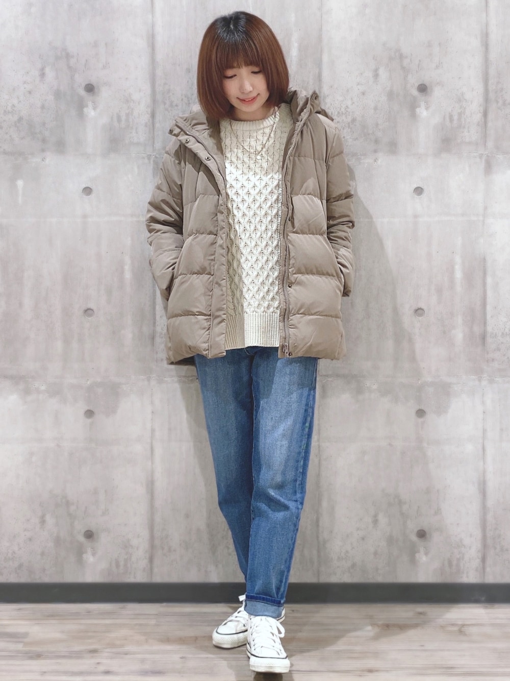 ベージュ系のダウンジャケット/コート、ホワイト系のニット/セーター、ブルー系のデニムパンツを着用したレディースの秋コーディネートの1枚目の写真