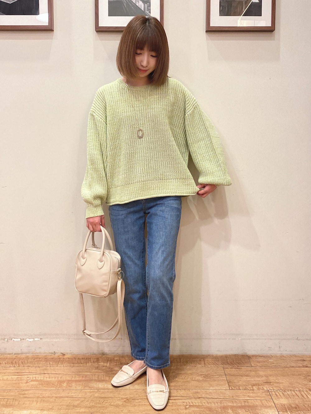 グリーン系のニット/セーター、ブルー系のデニムパンツ、ホワイト系のショルダーバッグを着用したレディースの冬コーディネートの1枚目の写真