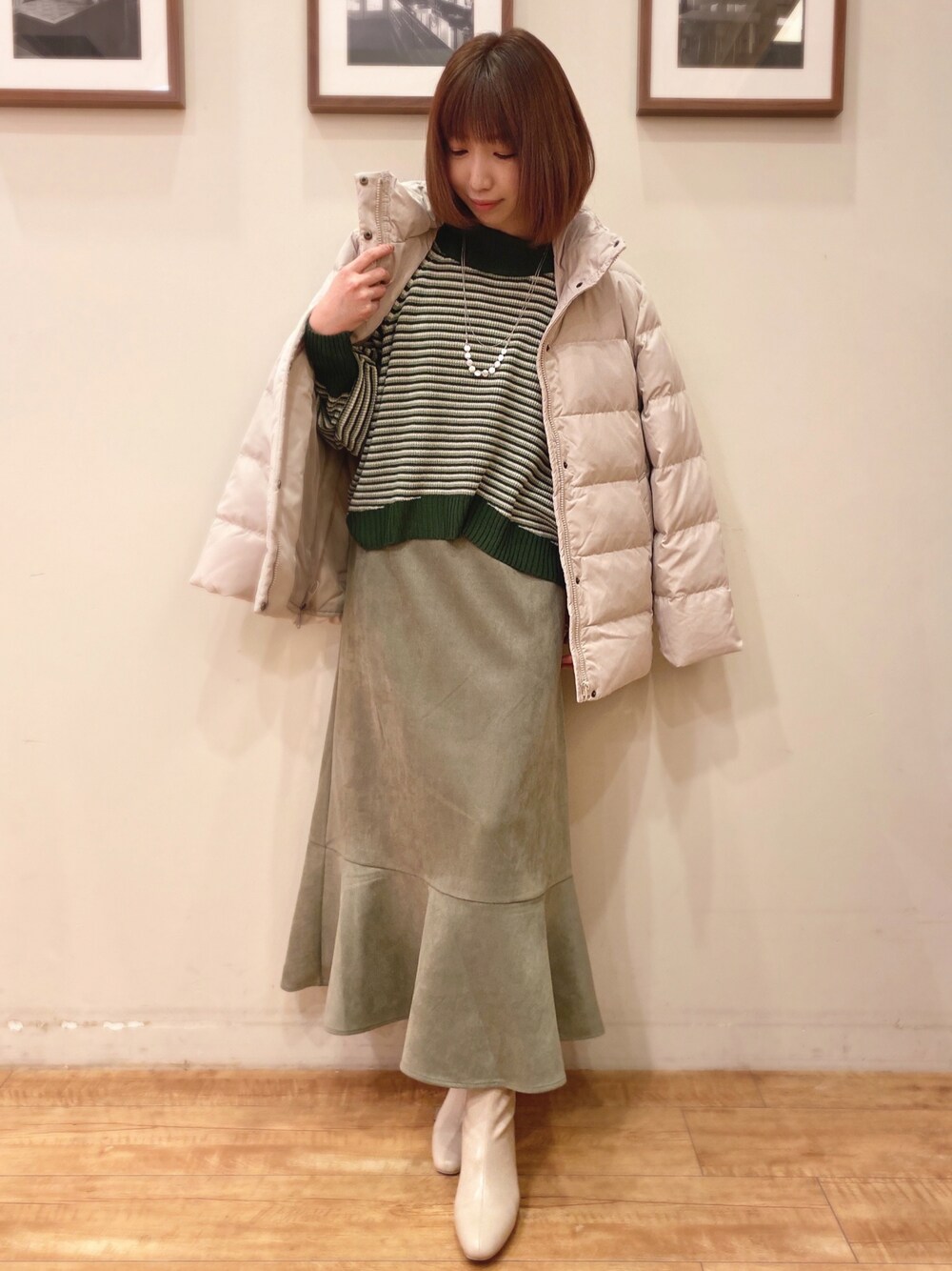 グリーン系のニット/セーター、グリーン系のスカート、ホワイト系のブーツを着用したレディースの冬コーディネートの1枚目の写真