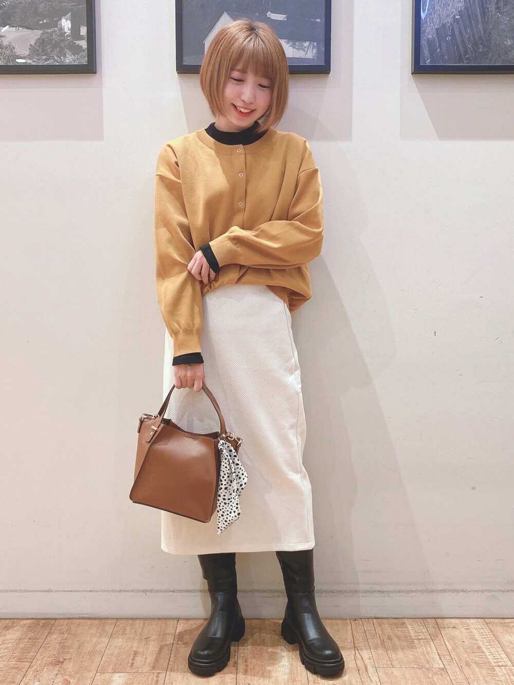 ブラック系のブーツ、イエロー系のカーディガン/ボレロ、ホワイト系のスカートを着用したレディースの秋コーディネートの1枚目の写真