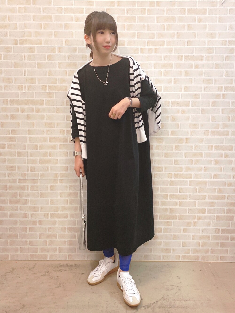 ブラック系のワンピース、ホワイト系のカーディガン/ボレロ、ホワイト系のスニーカーを着用したレディースの春コーディネートの1枚目の写真