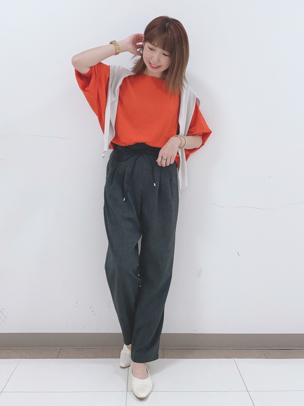 グレー系のカーディガン/ボレロ、オレンジ系のシャツ/ブラウス、グレー系のその他パンツを着用したレディースの春コーディネートの1枚目の写真