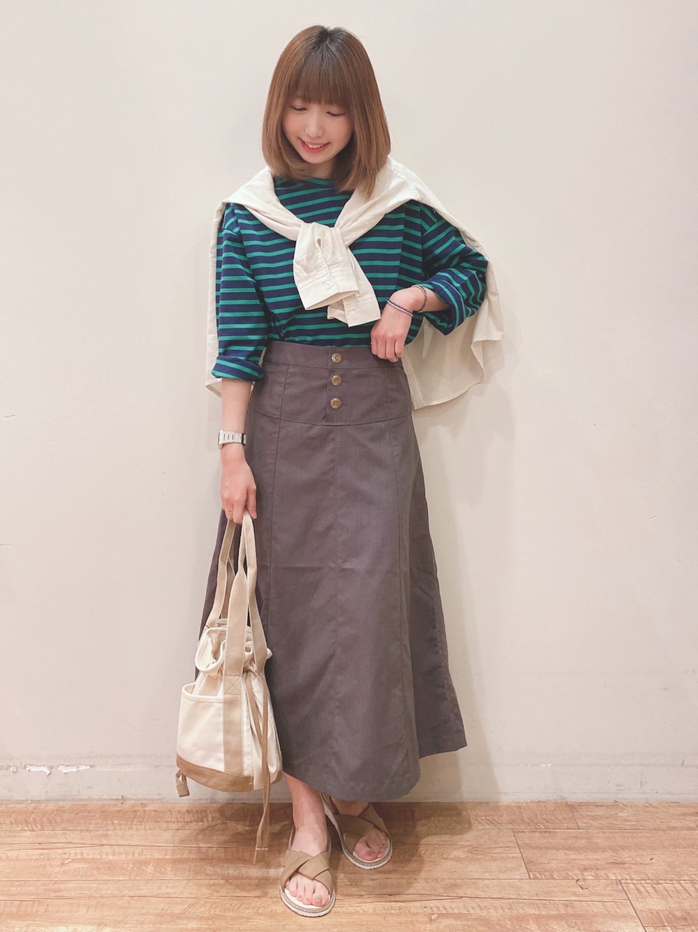 ブルー系のTシャツ/カットソー、ホワイト系のシャツ/ブラウス、グレー系のスカートを着用したレディースの春コーディネートの1枚目の写真