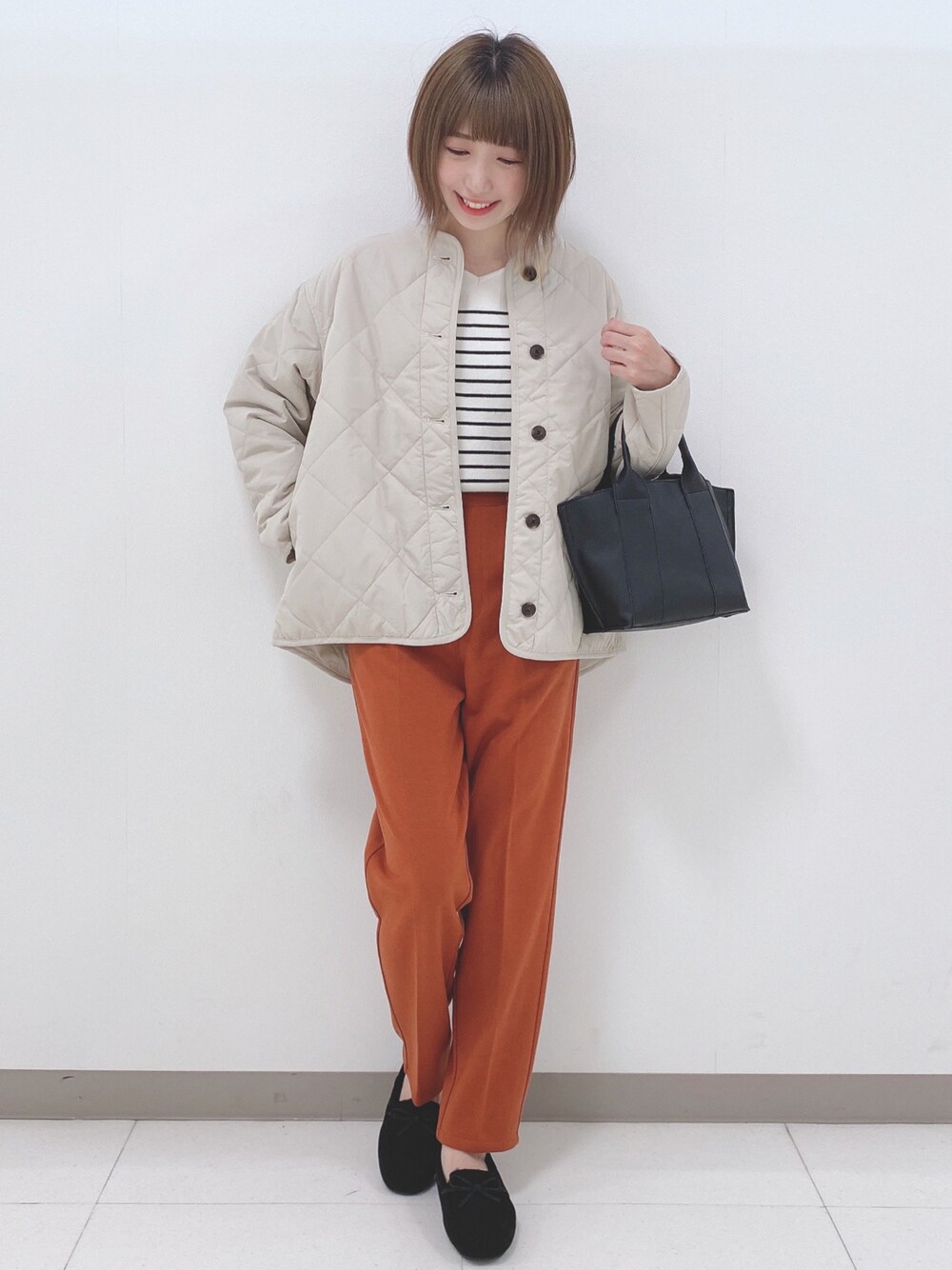 グレー系のブルゾン、ホワイト系のニット/セーター、オレンジ系のその他パンツを着用したレディースの秋コーディネートの1枚目の写真