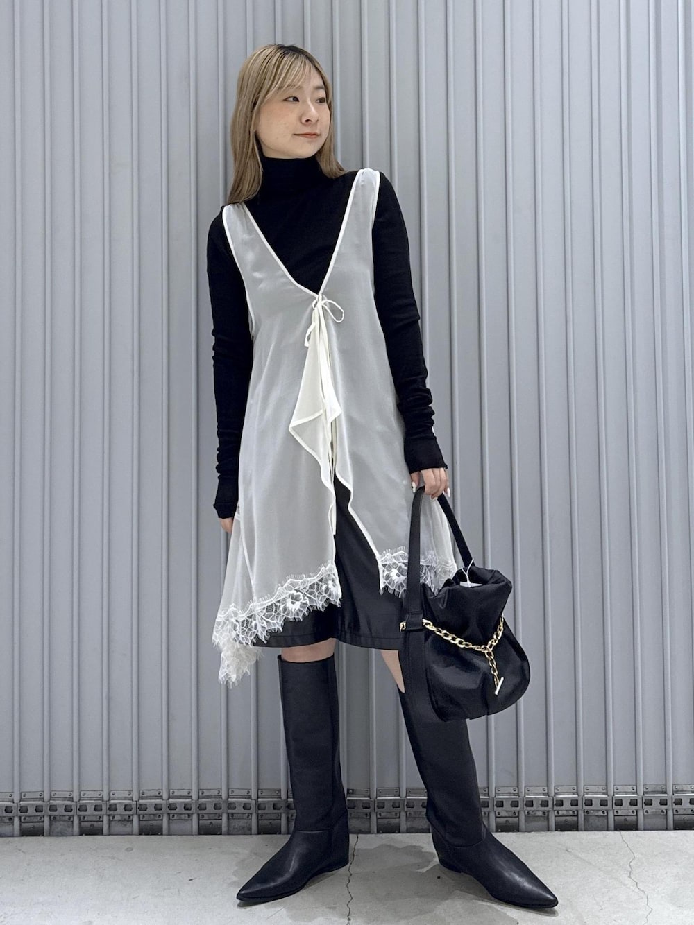 ブラック系のTシャツ/カットソー、ブラック系のブーツ、ブラック系のハンドバッグを着用したレディースの秋コーディネートの1枚目の写真