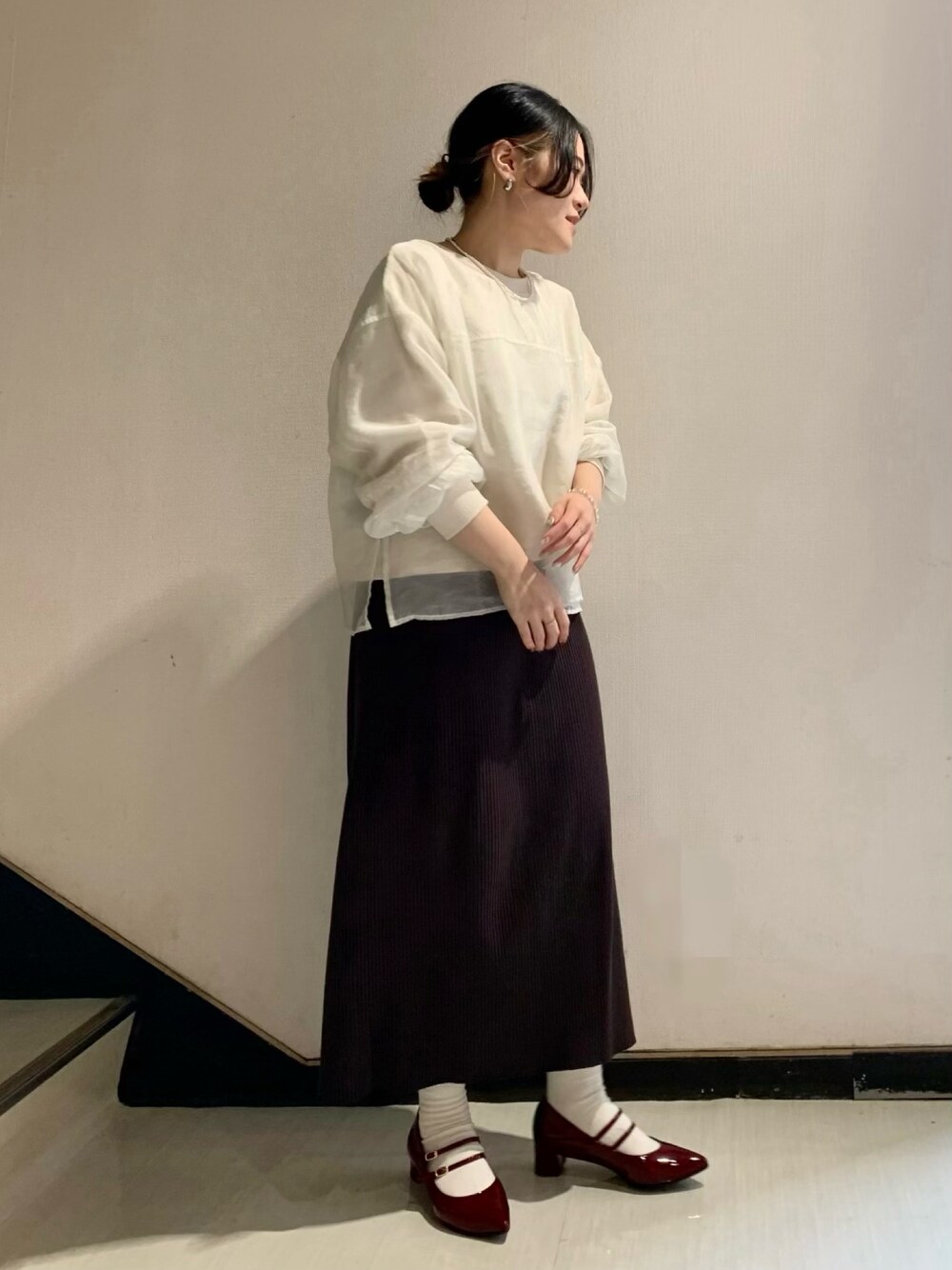 レッド系のパンプスを着用したレディースの秋コーディネートの1枚目の写真