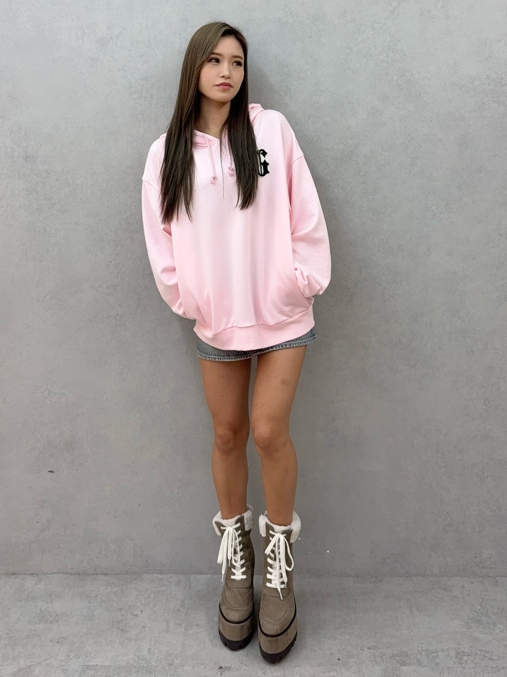 ピンク系のパーカー、ブルー系のデニムスカート、ベージュ系のブーツを着用したレディースの秋コーディネートの1枚目の写真