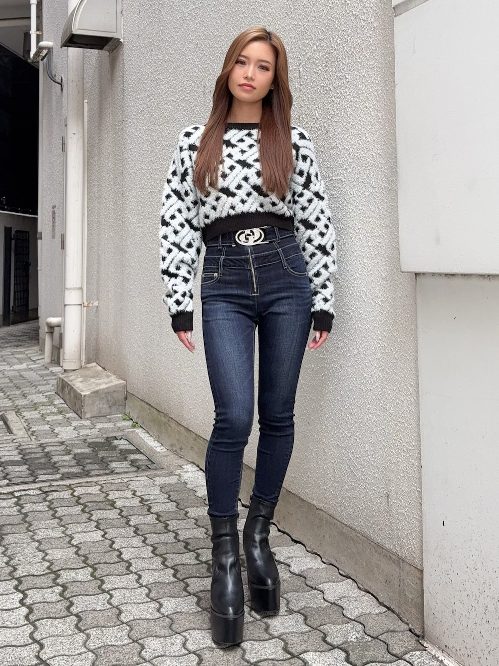 ブラック系のニット/セーター、ブルー系のデニムパンツ、ブラック系のブーツを着用したレディースの秋コーディネートの1枚目の写真