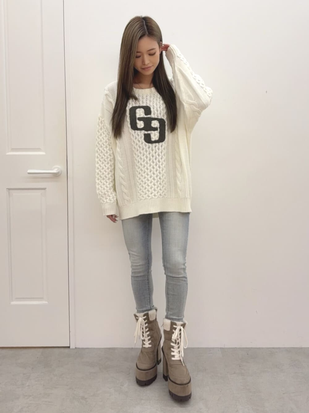 ブルー系のデニムパンツ、ベージュ系のブーツ、ホワイト系のニット/セーターを着用したレディースの秋コーディネートの1枚目の写真