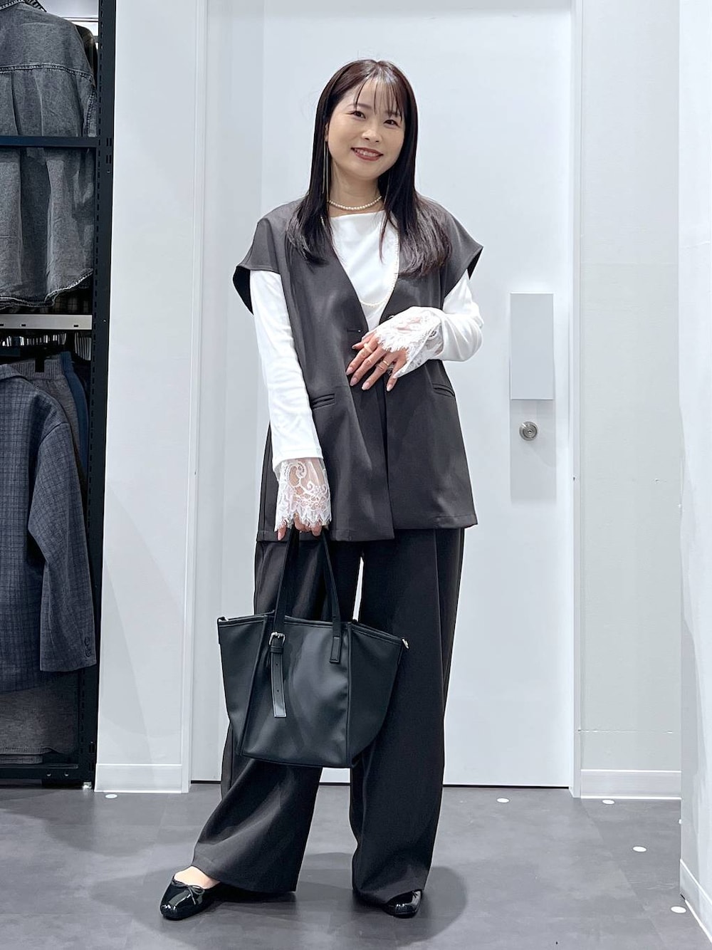 ブラック系のレインシューズ、ブラック系のトートバッグ、グレー系のベストを着用したレディースの冬コーディネートの1枚目の写真