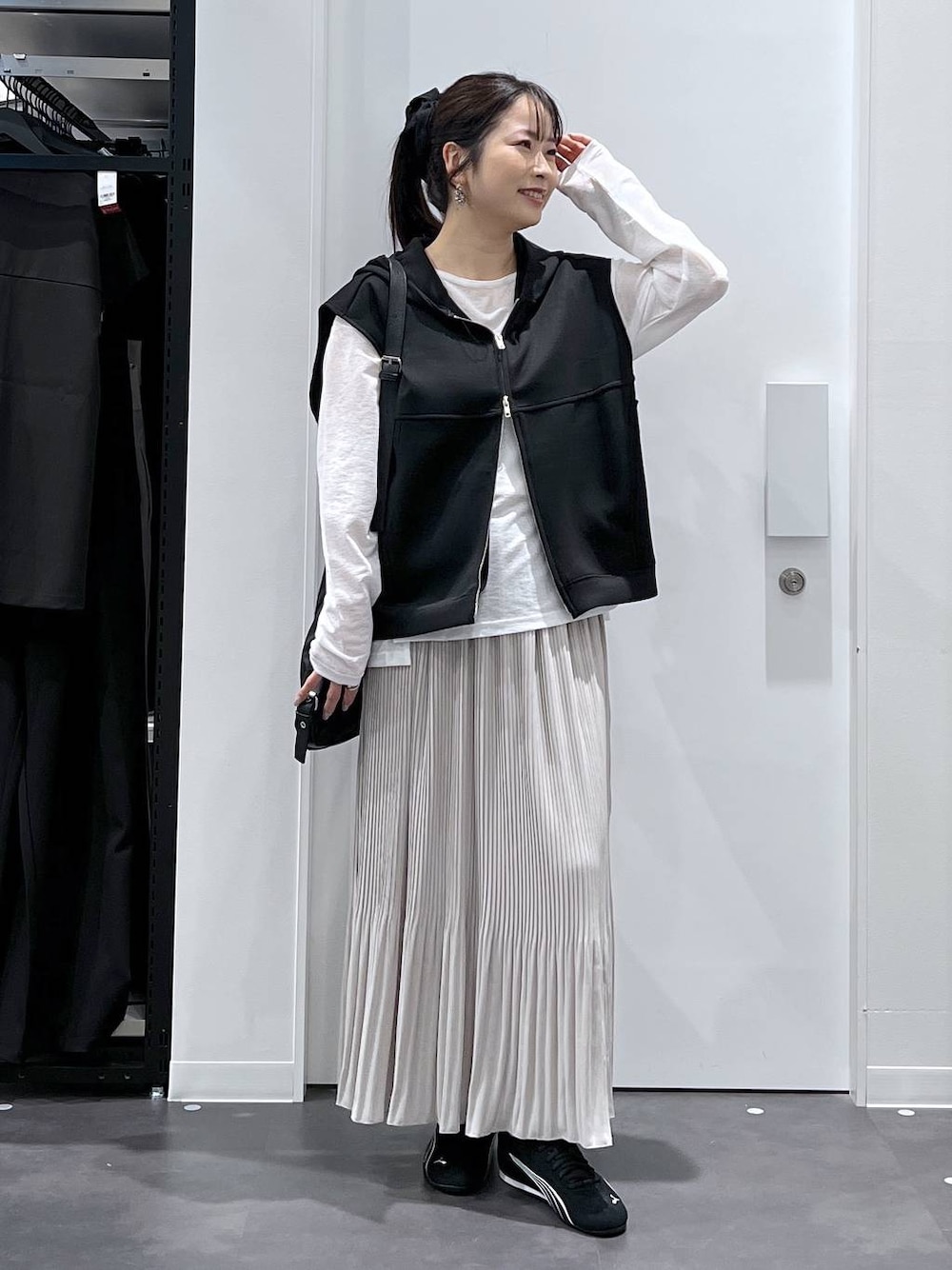 ブラック系のスニーカー、ブラック系のショルダーバッグ、ブラック系のベストを着用したレディースの春コーディネートの1枚目の写真