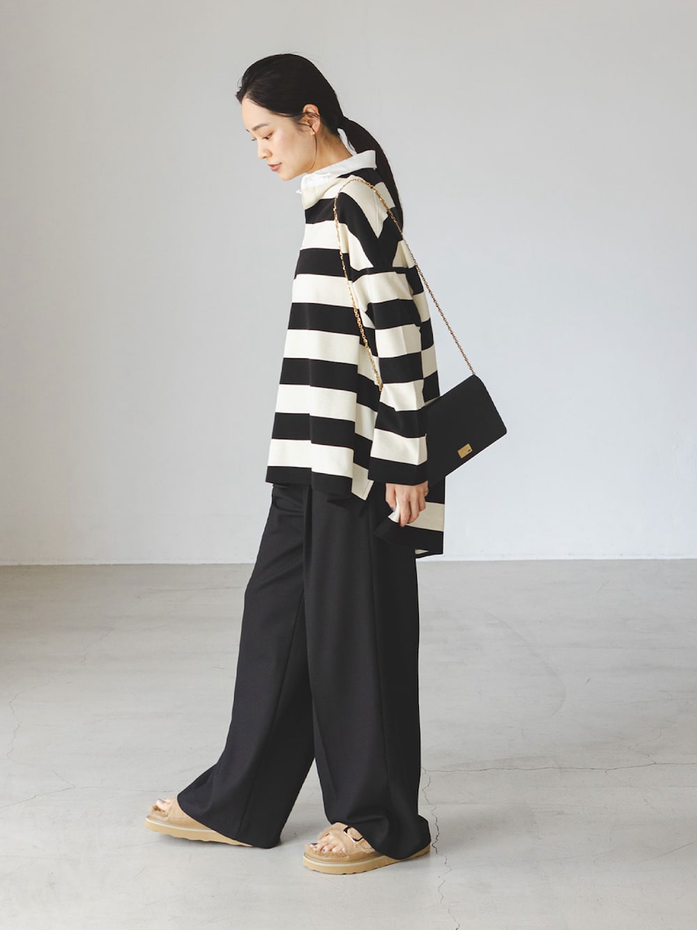 ホワイト系のTシャツ/カットソー、ブラック系のスラックス、ベージュ系のサンダルを着用したレディースの秋コーディネートの1枚目の写真