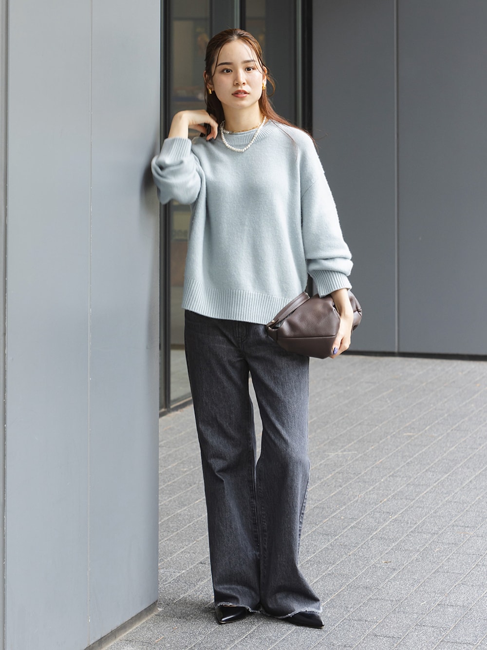 ブルー系のニット/セーター、ブラック系のデニムパンツ、ブラウン系のショルダーバッグを着用したレディースの秋コーディネートの1枚目の写真
