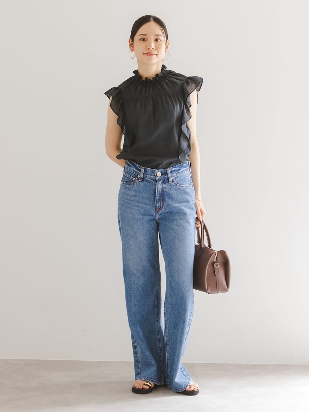 ブラック系のシャツ/ブラウス、ブルー系のデニムパンツ、ブラウン系のボストンバッグを着用したレディースの夏コーディネートの1枚目の写真