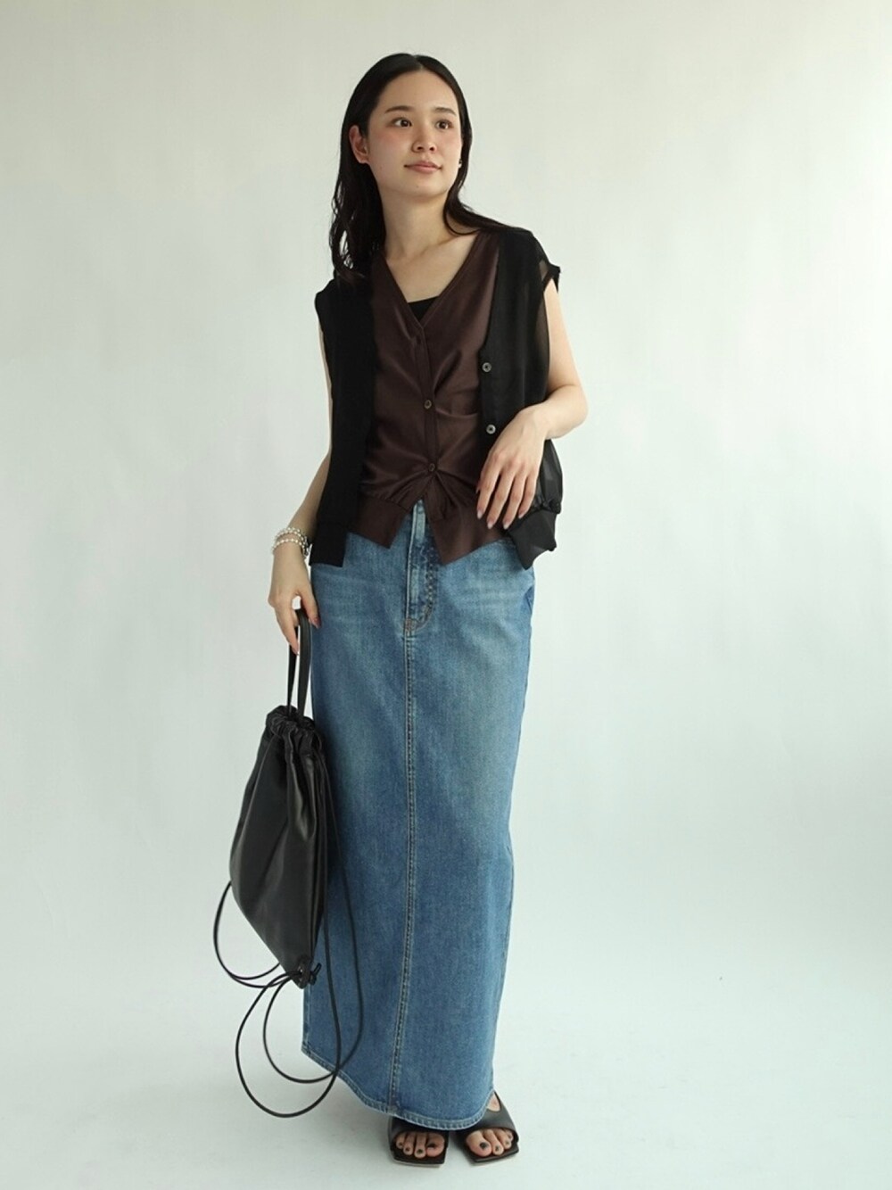 ブラック系のベスト、ブルー系のデニムスカートを着用したレディースの夏コーディネートの1枚目の写真