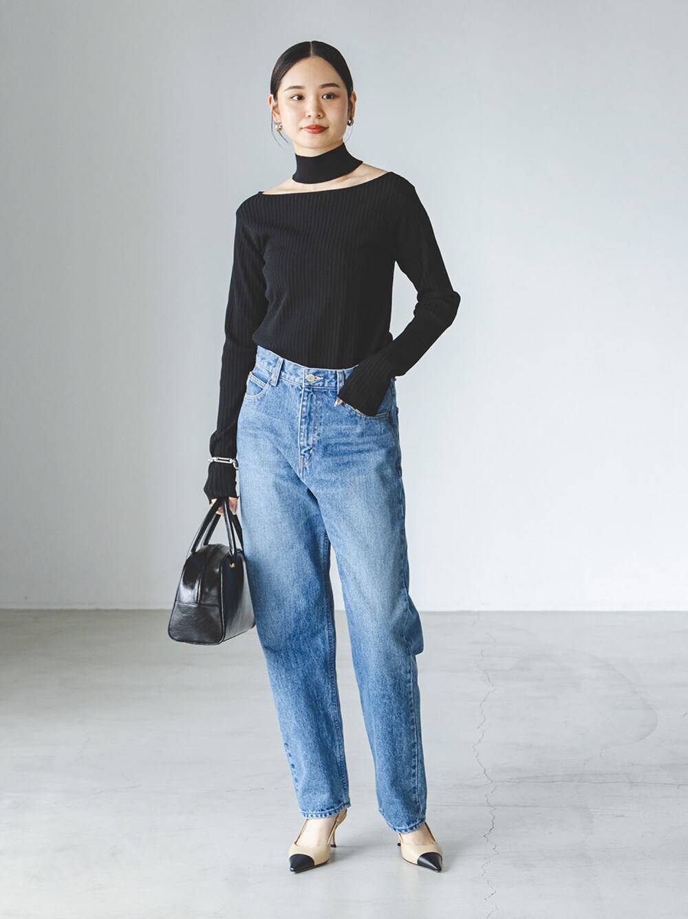 ブラック系のニット/セーター、ブルー系のデニムパンツを着用したレディースの夏コーディネートの1枚目の写真
