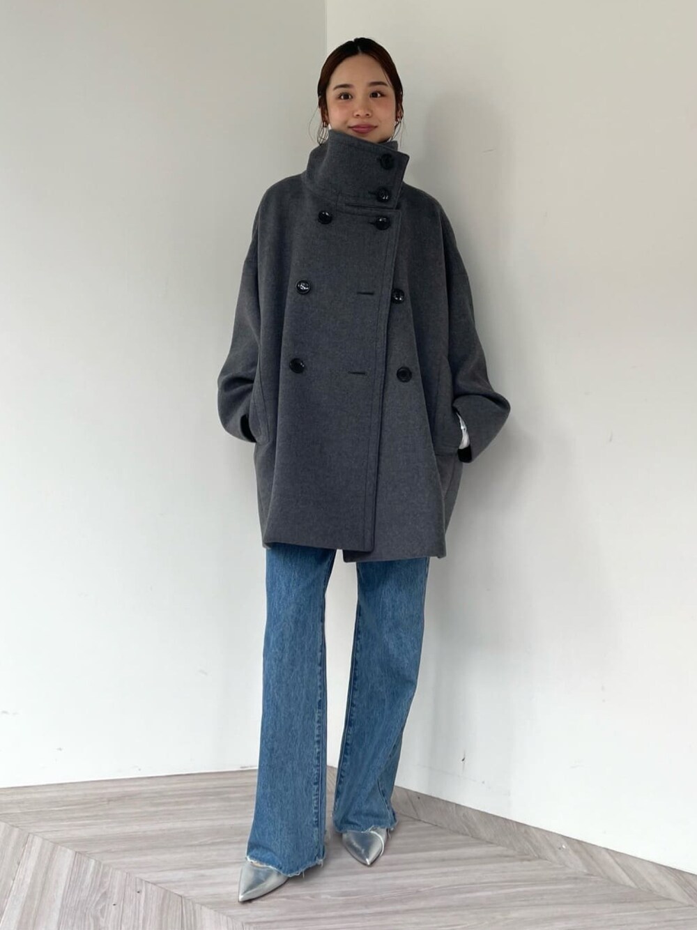 グレー系のその他アウター、シルバー系のパンプス、ブルー系のデニムパンツを着用したレディースの冬コーディネートの1枚目の写真