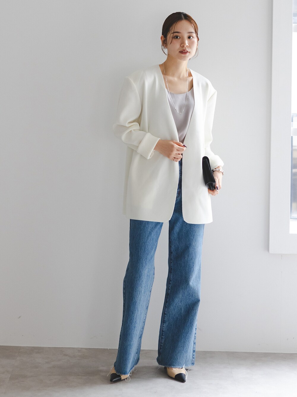 グレー系のタンクトップ、ホワイト系のカーディガン/ボレロ、ブルー系のデニムパンツを着用したレディースの秋コーディネートの1枚目の写真