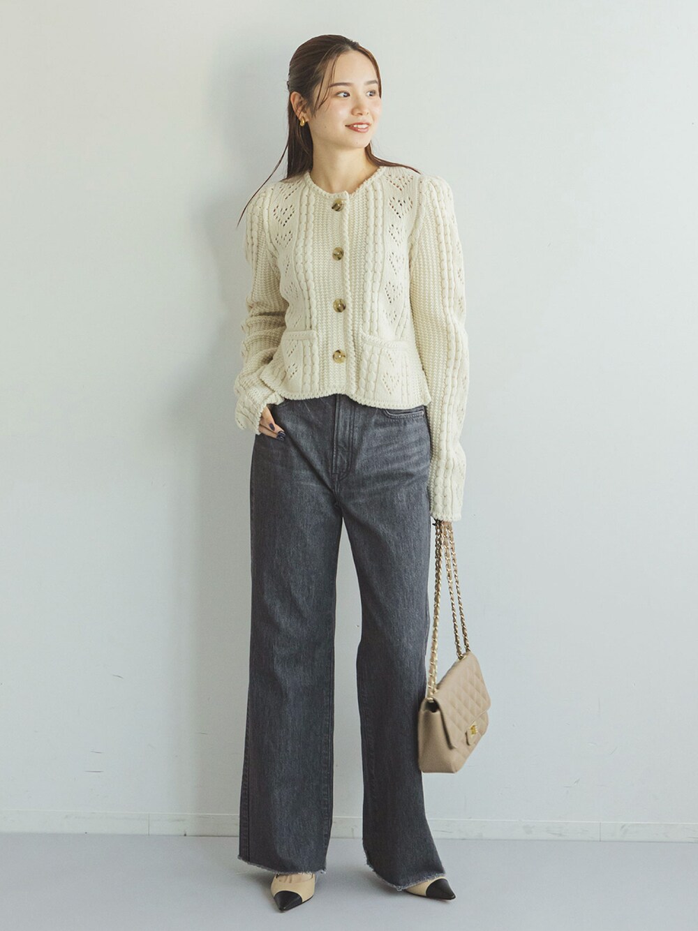 ホワイト系のカーディガン/ボレロ、ブラック系のデニムパンツ、ベージュ系のショルダーバッグを着用したレディースの秋コーディネートの1枚目の写真