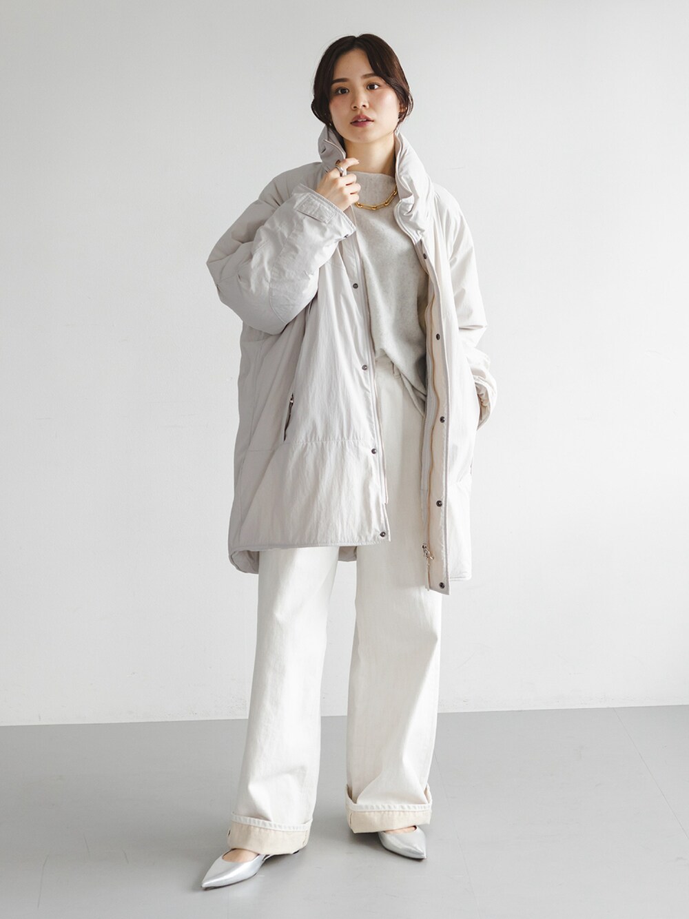 ホワイト系のダウンジャケット/コート、グレー系のニット/セーター、ホワイト系のデニムパンツを着用したレディースの秋コーディネートの1枚目の写真