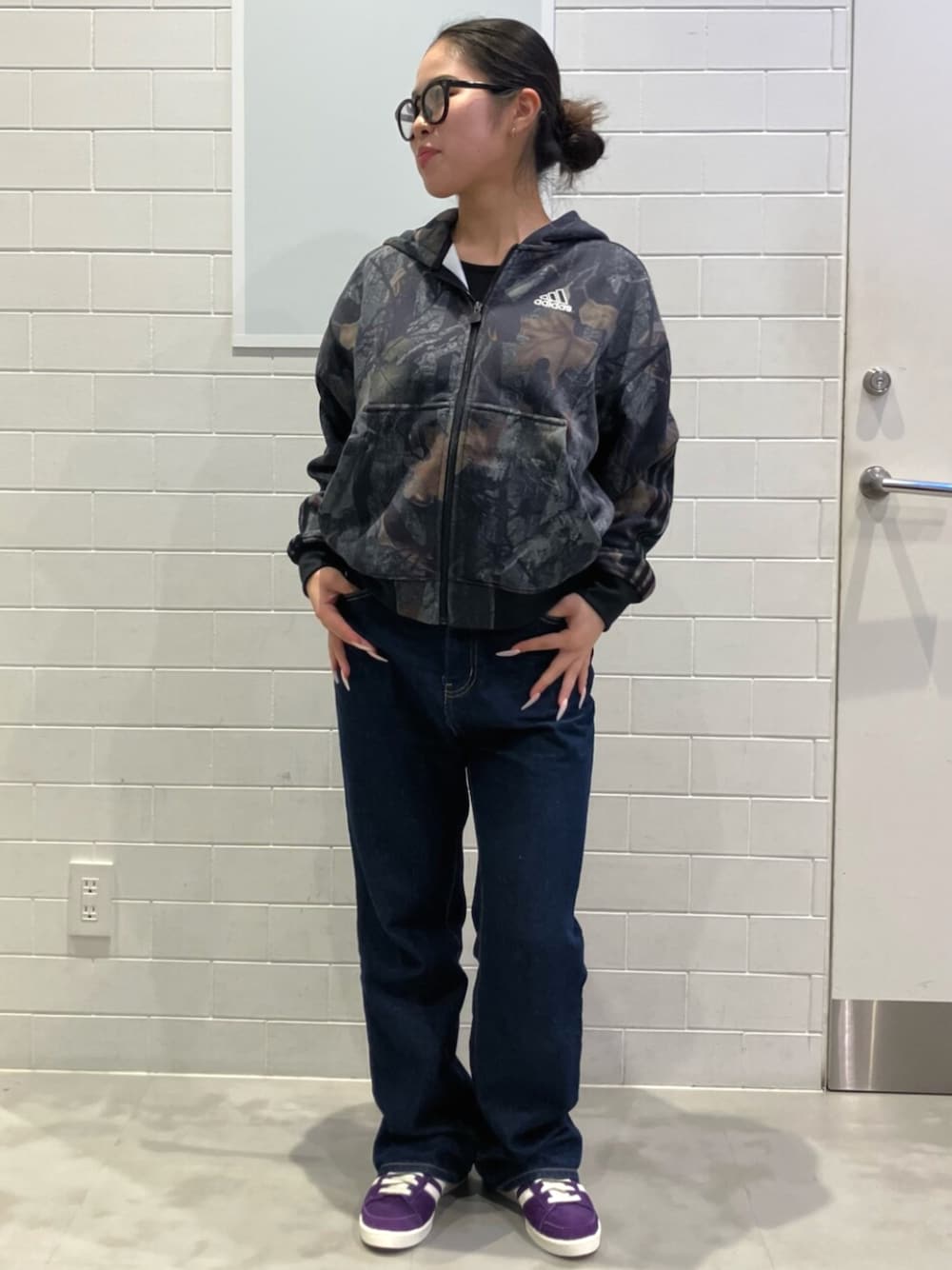 ブラック系のパーカー、パープル系のスニーカーを着用したレディースの秋コーディネートの1枚目の写真