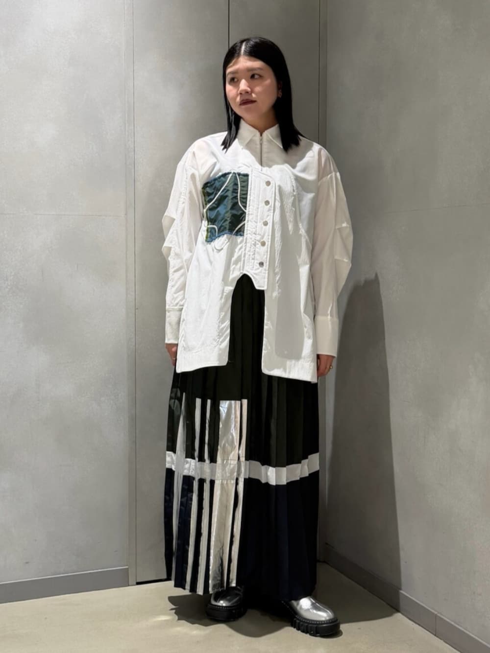 ホワイト系のシャツ/ブラウス、グリーン系のスカート、シルバー系のブーツを着用したレディースの春コーディネートの1枚目の写真