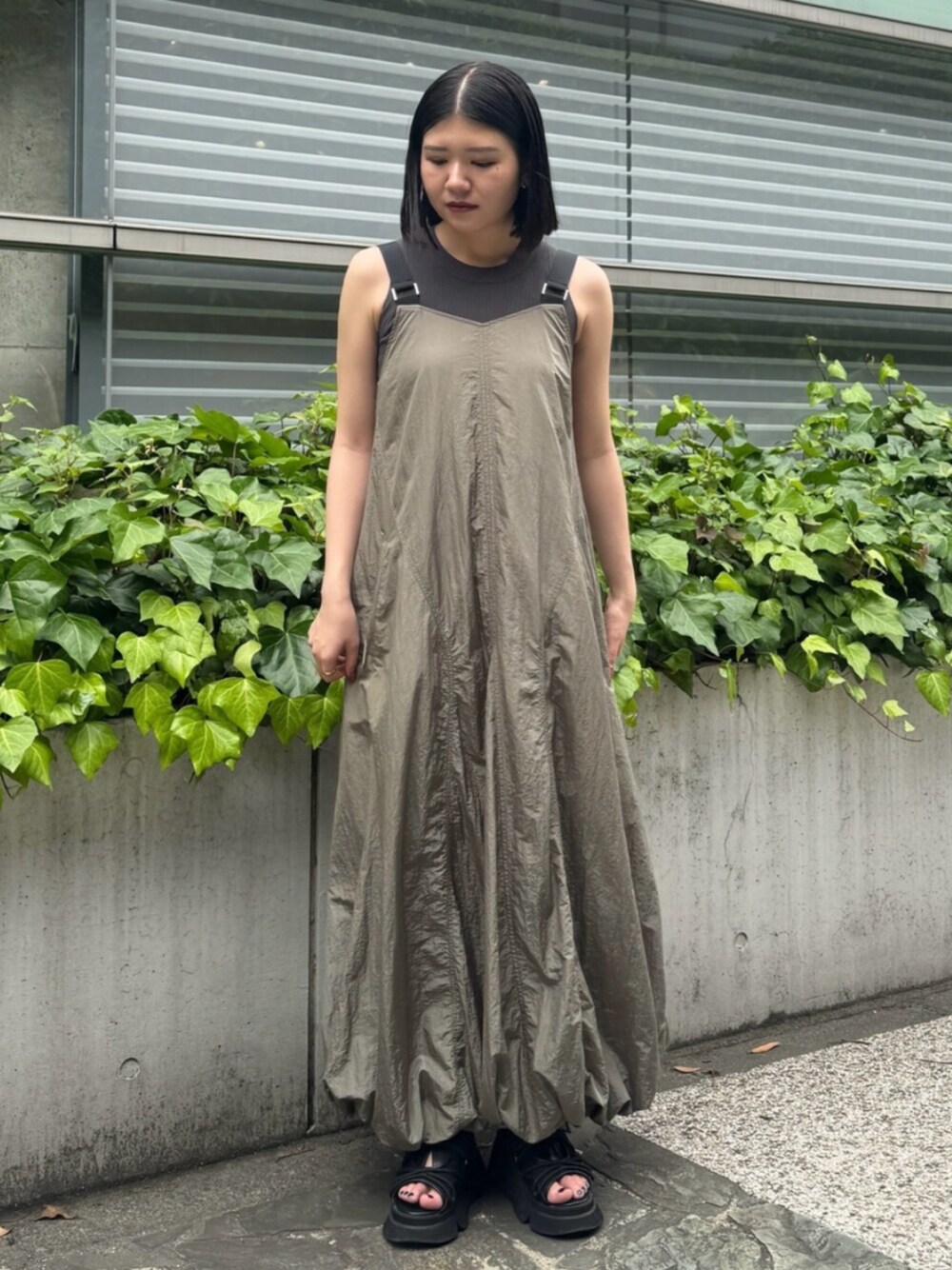 ブラック系のサンダル、ベージュ系のワンピースを着用したレディースの夏コーディネートの1枚目の写真