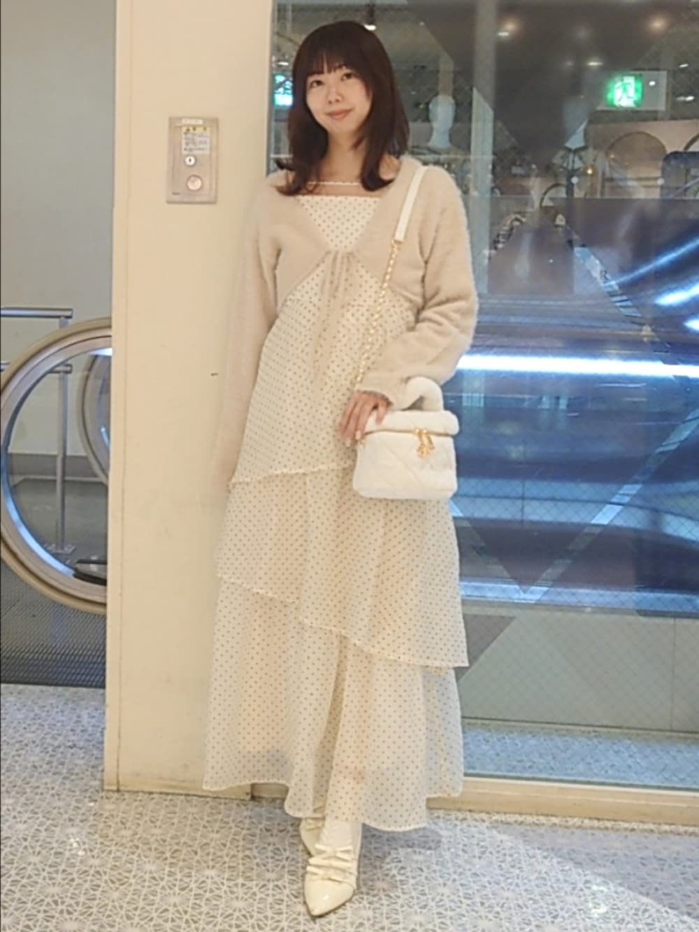ベージュ系のワンピース、ホワイト系のショルダーバッグ、ホワイト系のパンプスを着用したレディースの秋コーディネートの1枚目の写真