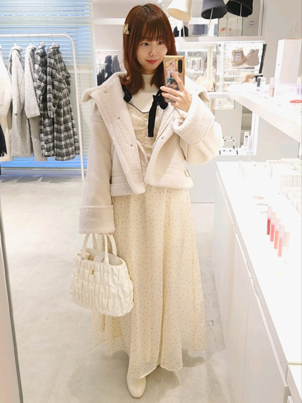 ホワイト系のブーツ、ホワイト系のハンドバッグ、ホワイト系のムートンコートを着用したレディースの冬コーディネートの1枚目の写真