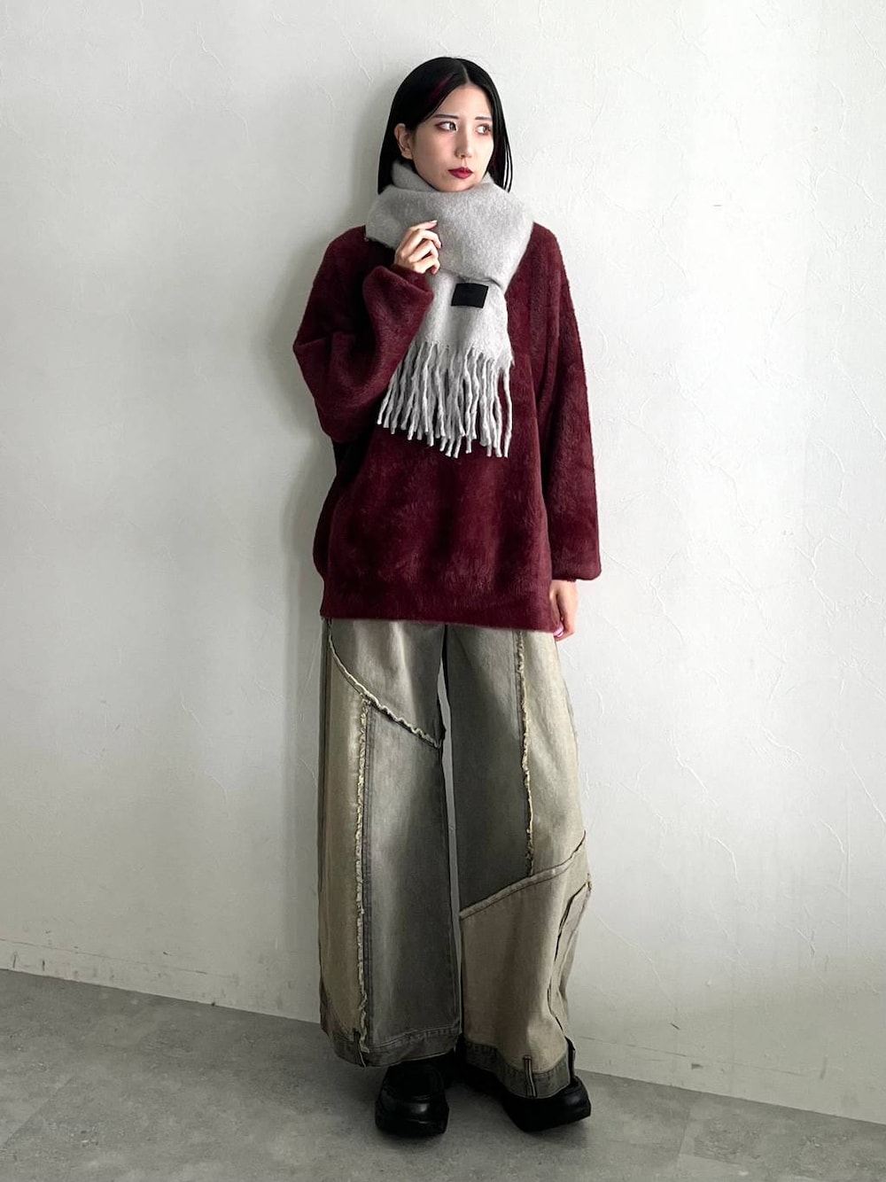 レッド系のニット/セーター、ブラック系のスニーカー、ベージュ系のデニムパンツを着用したレディースの秋コーディネートの1枚目の写真