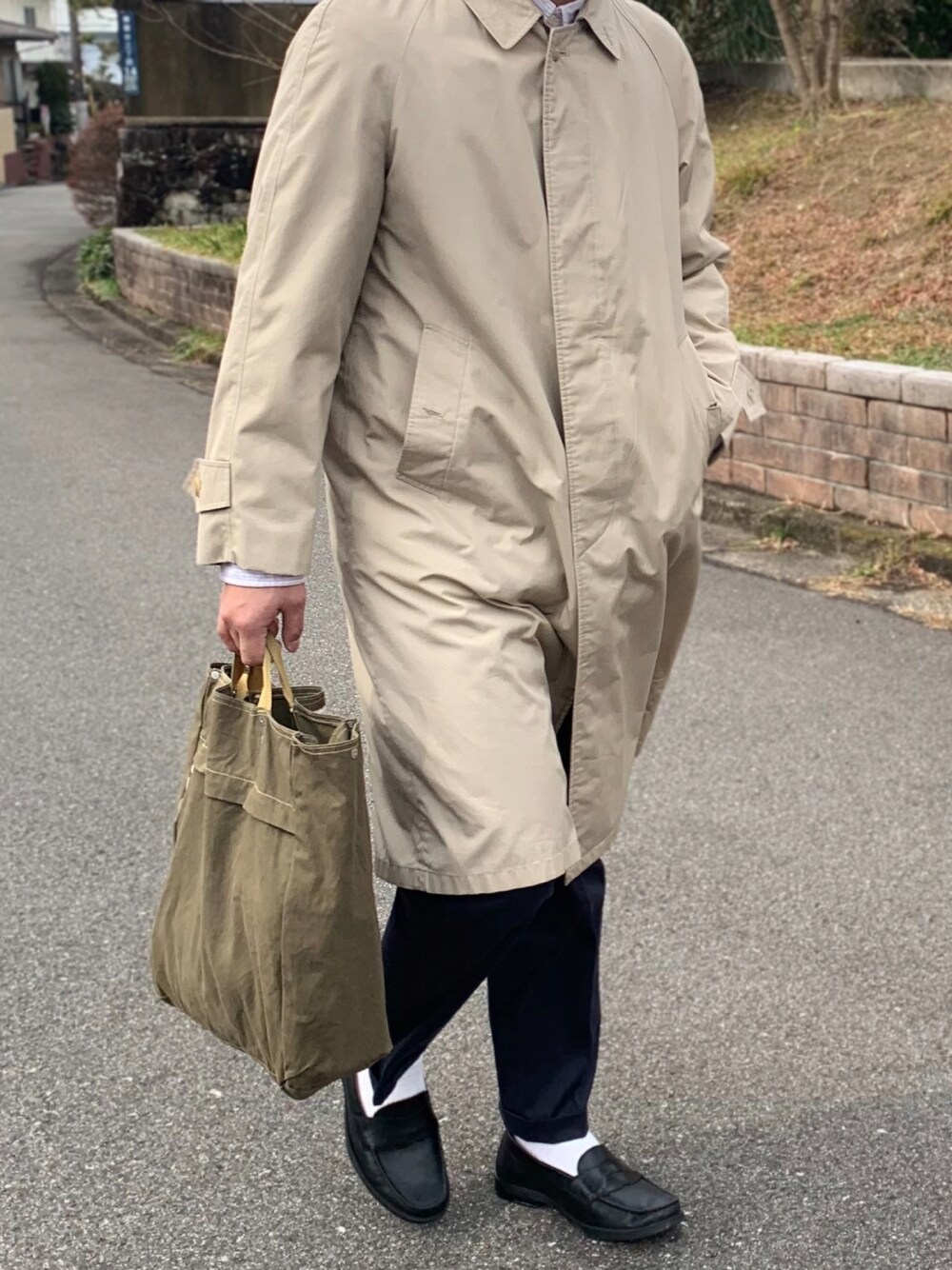 グリーン系のトートバッグ、ブラック系のパンツを着用したメンズの冬コーディネートの1枚目の写真