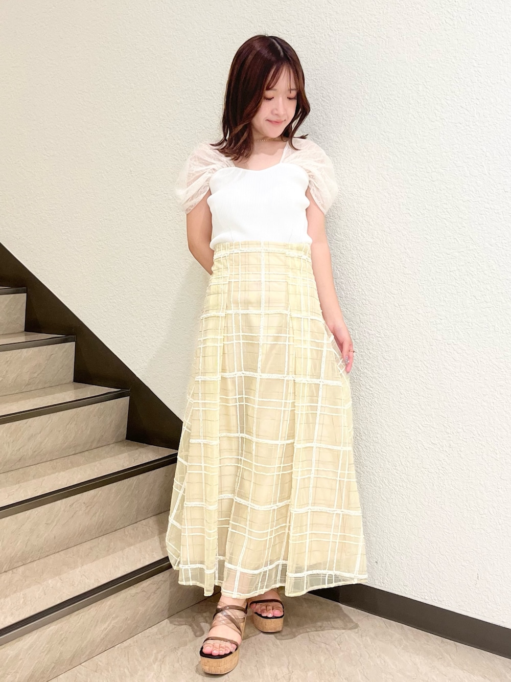 ホワイト系のニット/セーター、イエロー系のスカート、ブラック系のサンダルを着用したレディースの夏コーディネートの1枚目の写真