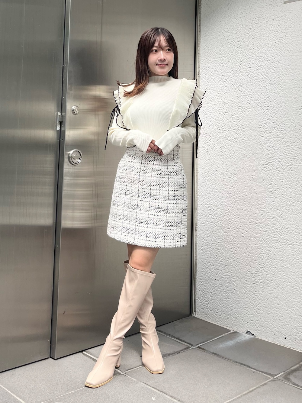 ホワイト系のニット/セーター、ホワイト系のスカート、ベージュ系のブーツを着用したレディースの秋コーディネートの1枚目の写真