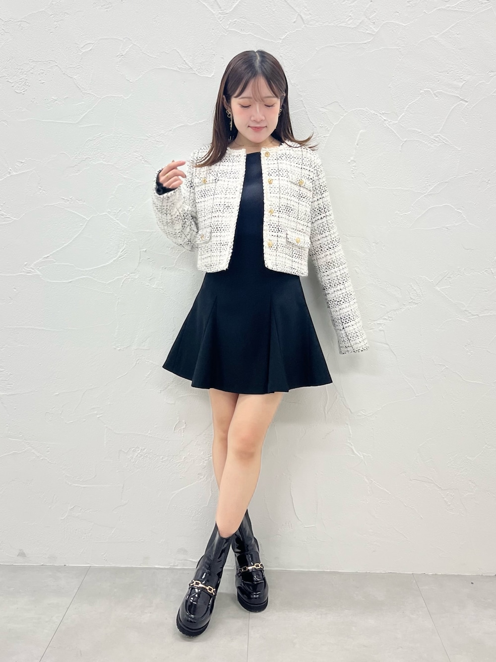 ホワイト系のノーカラージャケット、ブラック系のスカート、ブラック系のブーツを着用したレディースの秋コーディネートの1枚目の写真