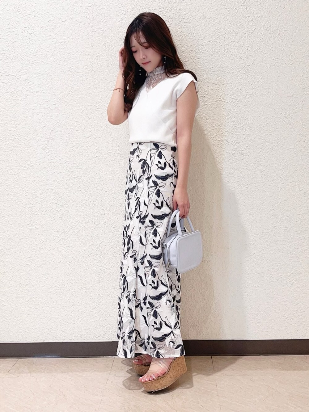 ホワイト系のニット/セーター、ホワイト系のスカート、その他のサンダルを着用したレディースの春コーディネートの1枚目の写真