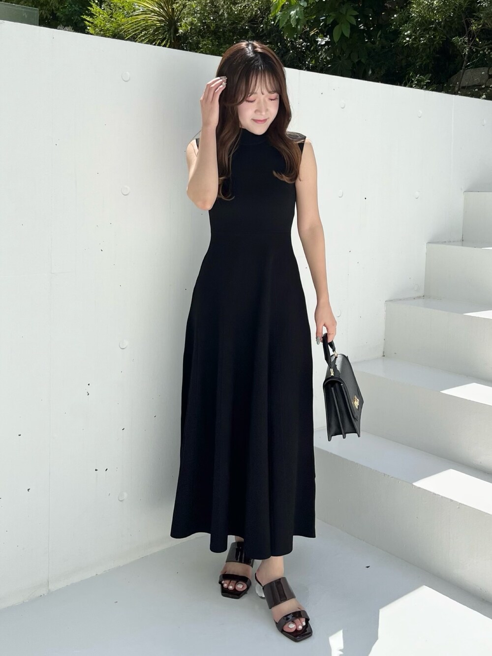 ブラック系のワンピース、ブラウン系のサンダル、ブラック系のハンドバッグを着用したレディースの春コーディネートの1枚目の写真