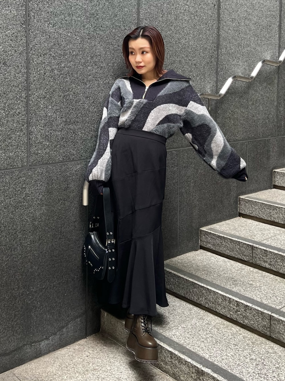 ブラック系のニット/セーター、ブラウン系のブーツ、ブラック系のスカートを着用したレディースの秋コーディネートの1枚目の写真