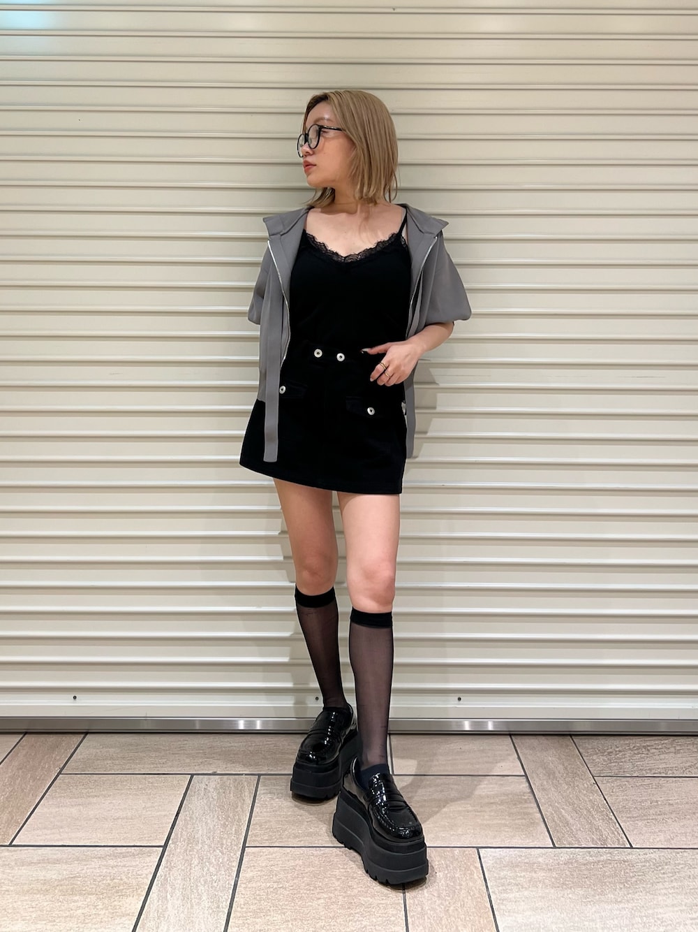 グレー系のパーカー、ブラック系のスカートを着用したレディースの夏コーディネートの1枚目の写真
