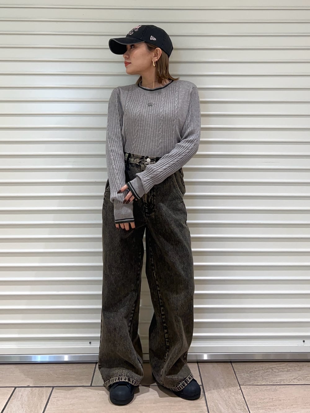 グレー系のニット/セーター、ブラック系のデニムパンツ、ブラック系のキャップを着用したレディースの冬コーディネートの1枚目の写真