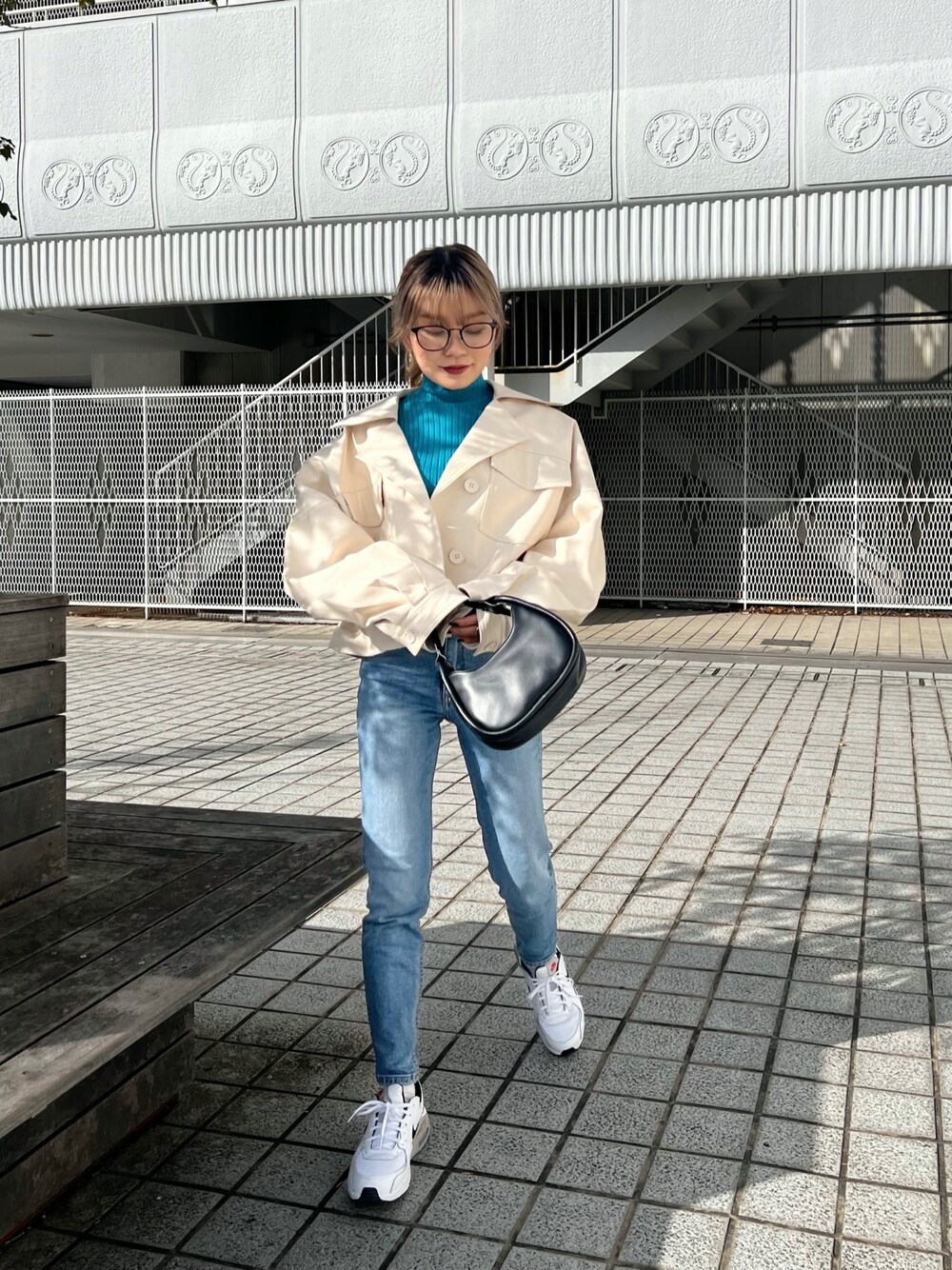 ホワイト系のライダースジャケット、ブルー系のニット/セーター、ブラック系のハンドバッグを着用したレディースの冬コーディネートの1枚目の写真