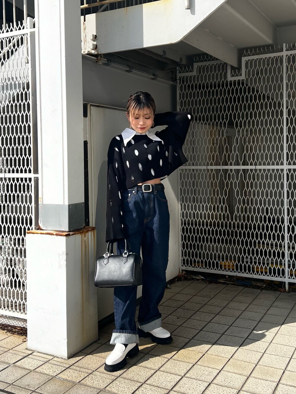 ブルー系のデニムパンツ、ホワイト系のローファー、ブラック系のニット/セーターを着用したレディースの冬コーディネートの1枚目の写真