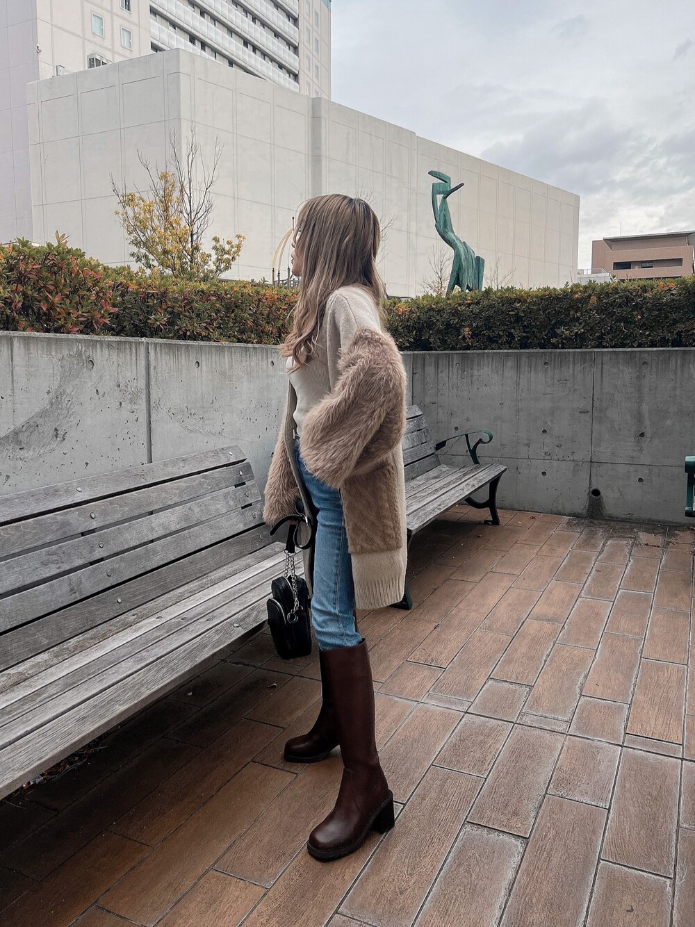 ホワイト系のニット/セーター、ベージュ系のカーディガン/ボレロ、ブラウン系のブーツを着用したレディースの冬コーディネートの1枚目の写真