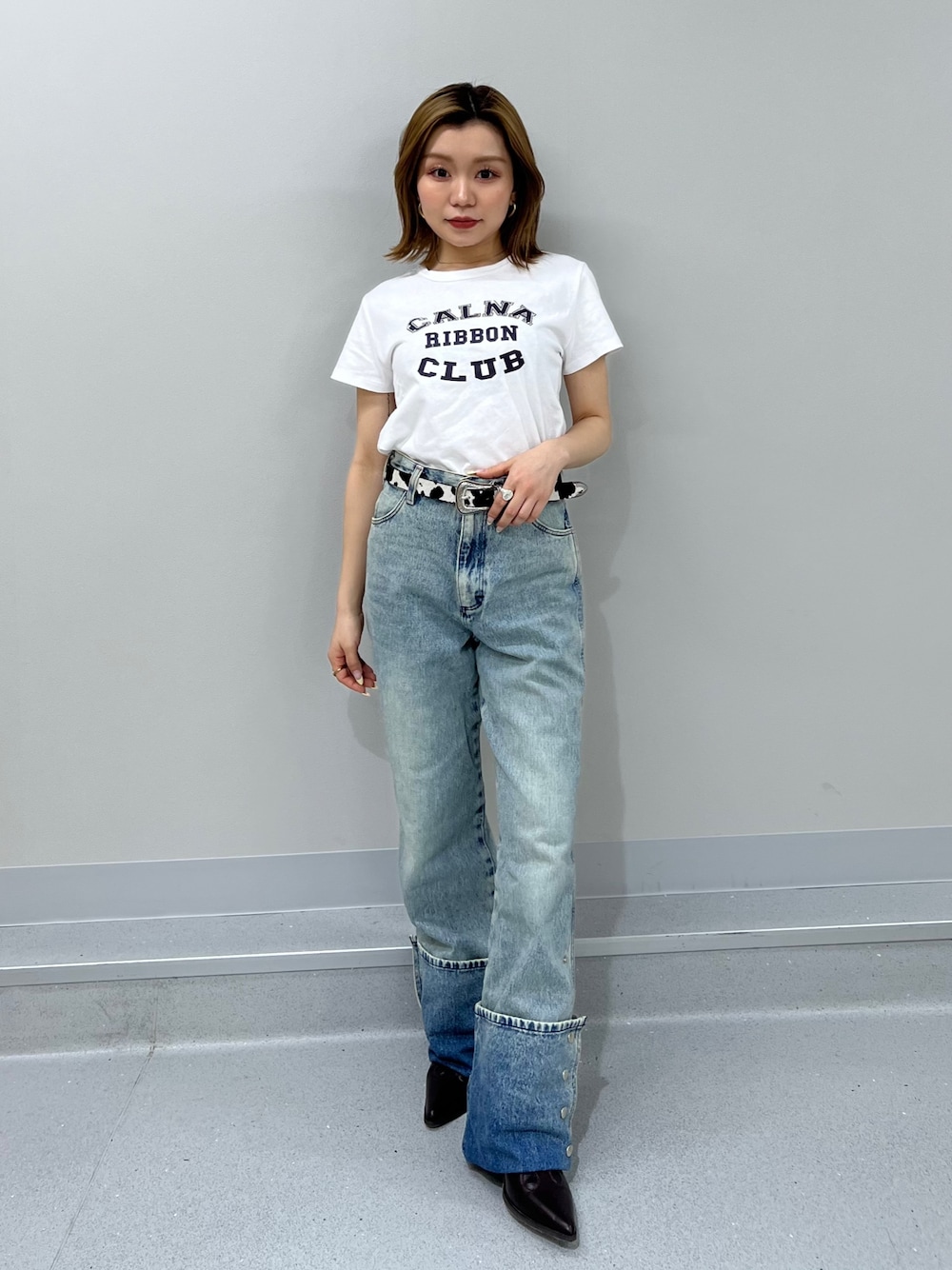 ブルー系のデニムパンツ、ホワイト系のTシャツ/カットソー、ブラウン系のブーツを着用したレディースの春コーディネートの1枚目の写真