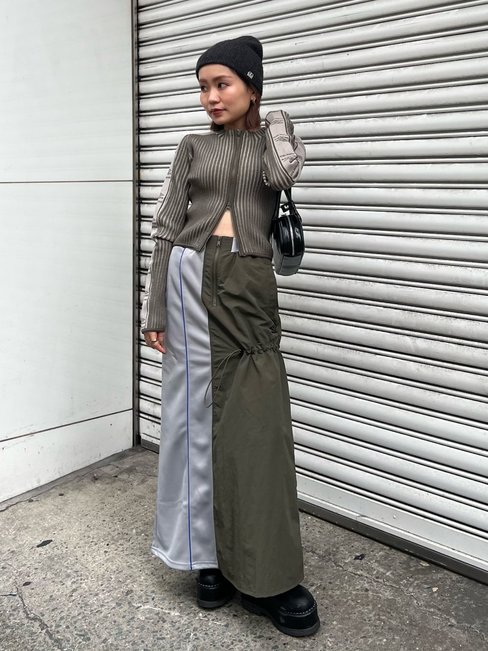 ブラック系のブーツ、グリーン系のニット/セーター、グリーン系のスカートを着用したレディースの秋コーディネートの1枚目の写真