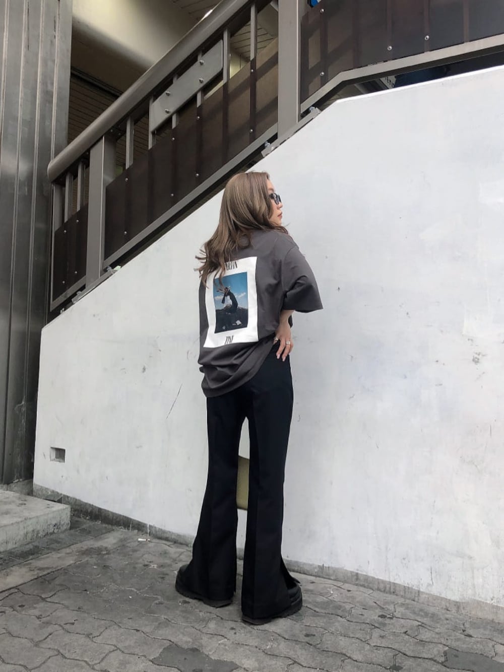 ブラック系のスラックス、ホワイト系のハンドバッグ、グレー系のTシャツ/カットソーを着用したレディースの春コーディネートの1枚目の写真