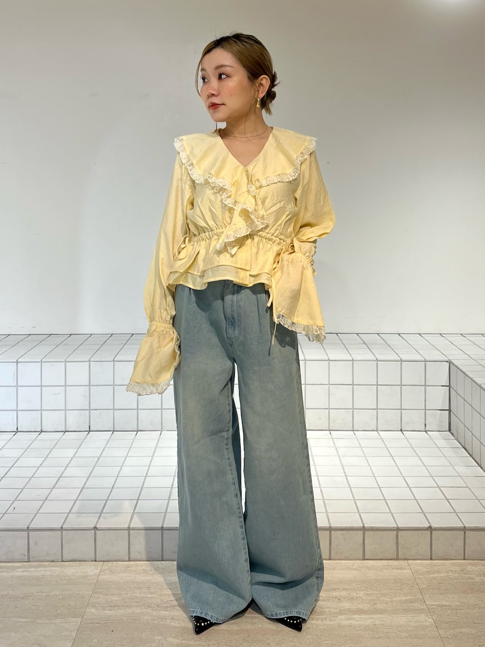 ブルー系のデニムパンツ、イエロー系のシャツ/ブラウス、ブラック系のサンダルを着用したレディースの春コーディネートの1枚目の写真